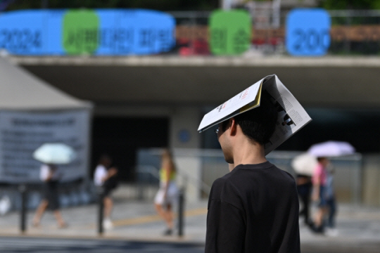 서울 중구 시청역 인근에서 한 시민이 종이로 햇볕을 가린 채 길을 걷고 있다. 박윤슬 기자