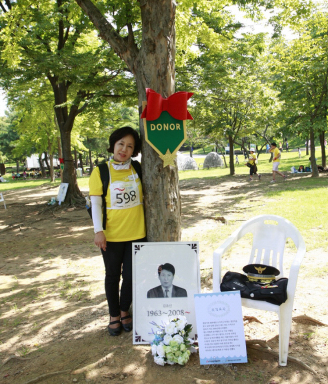 지난 2014년 9월 9일 서울 송파구 올림픽공원 내 ‘1일 추모공원’에서 2008년 4명에게 장기기증을 하고 떠난 고 김유신 경감의 아내 정선자 씨가 남편의 사진과 제복을 옆에 두고 추모하고 있다. 정선자 씨 제공
