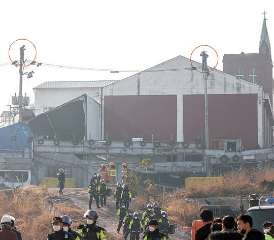 서울 성북구 사랑제일교회 신도 2명이 지난 2021년 11월 15일 서울북부지방법원의 교회건물 철거 6차 명도집행 도중 전봇대(점선) 위에 올라가 기도하고 있다. 뉴시스