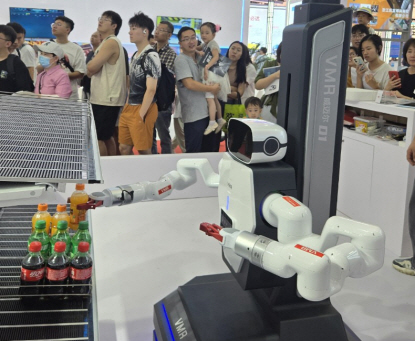 매대에서 물건을 정리하고 있는 로봇을 관람객들이 바라보고 있다.