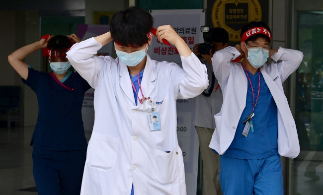 보건의료노조가 오는 29일 ‘진료 정상화’ 등을 요구하며 총파업을 예고한 가운데 26일 오전 서울 중구 국립중앙의료원에서 조합원들이 출근길 선전전을 위해 붉은색 머리띠를 묶으며 이동하고 있다.   문호남 기자