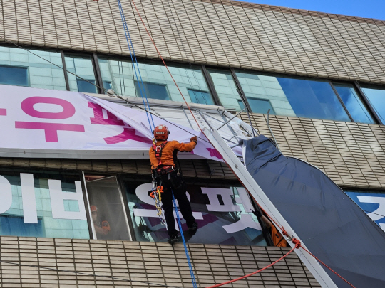 소방대원들이 29일 낮 12시 46분 부산 북구 덕천동 건물에서 이탈이 우려되는 간판의 안전 조치를 하고 있다. 부산소방재난본부 제공