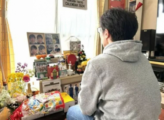 사랑니 발치 치료를 하다가 숨진 아들 사진을 바라보며 슬픔에 잠겨 있는 아버지 유오(48)씨. 산케이신문 캡처