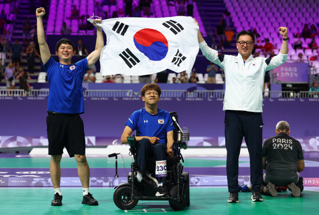 정호원(가운데)이 3일 프랑스 파리 사우스 아레나1에서 열린 2024 파리패럴림픽 보치아 남자 개인전(스포츠등급 BC3) 결승에서 승리한 뒤 임광택(오른쪽) 감독, 김승겸 코치와 함께 태극기를 들고 세리머니를 하고 있다. 로이터 연합뉴스
