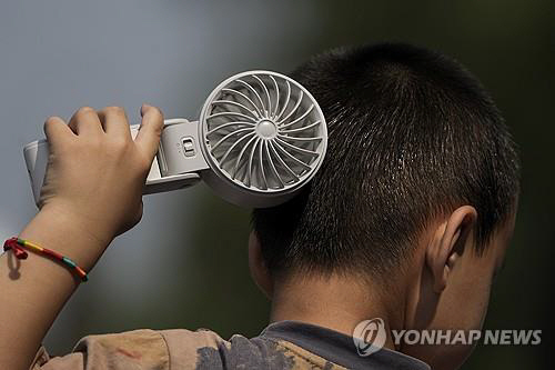 중국에서 한 소년이 휴대용 선풍기로 더위를 식히는 모습. AP 연합뉴스