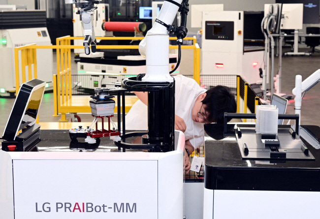 LG전자 관계자가 지난 12일 경기 평택시 LG전자 생산기술원 내 스마트팩토리확산센터에 전시된 수직다관절로봇을 가동하고 있다. 라인 내 실시간 영상을 촬영해 이상 유무를 감지하는 이 로봇은 반도체 웨이퍼 생산과정에서 공급 공정을 수행하는 데 용이하다.  LG전자 제공