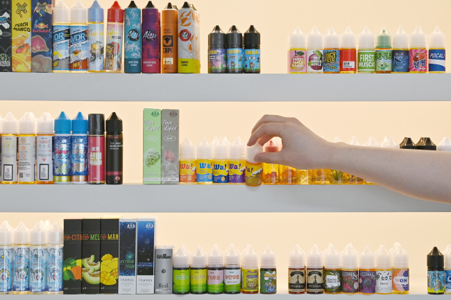 식품의약품안전처가 내년 상반기 중 ‘합성 니코틴’ 액상 전자담배 성분 분석 시험방법을 마련키로 한 가운데 24일 오전 서울 시내 한 액상 전자담배 판매점에서 직원이 진열된 제품을 꺼내고 있다.   백동현 기자