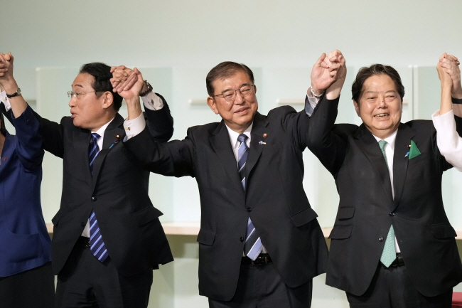 이시바 시게루(가운데) 신임 자민당 총재가 지난 27일 일본 도쿄 자민당 본부에서 열린 총재 선거에서 승리한 후 기시다 후미오(왼쪽) 총리, 하야시 요시마사 관방장관(오른쪽)과 손을 잡고 축하하고 있다. AP 연합뉴스
