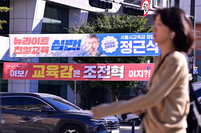 오는 16일 서울시교육감 보궐선거를 앞두고 4일 오전 서울 중구 신당역 인근 거리에 설치된 현수막 앞을 한 시민이 걸어가고 있다. 문호남 기자