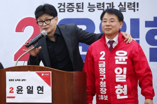 한동훈 국민의힘 당 대표가 지난달 27일 부산 금정구청장 보궐선거에 출마한 윤일현 후보 선거사무소에서 열린 개소식에서 윤 후보와 함께 인사하고 있다. 연합뉴스