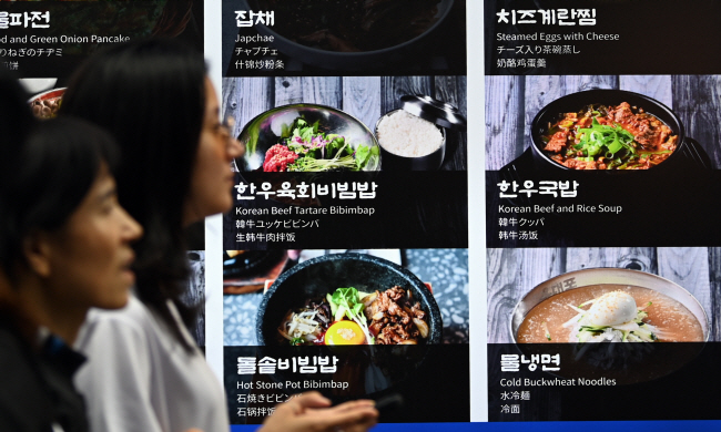 물가 상승으로 가구당 식품비 지출액이 급증한 가운데 13일 서울 도심에서 시민들이 비빔밥 등 한식 메뉴를 판매하는 식당 앞을 지나가고 있다. 한국소비자원에 따르면 서울 기준 비빔밥은 지난 8월 1만962원에서 지난달 1만1038원으로 한 달새 76원이 올랐다. 박윤슬 기자