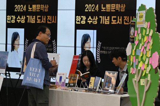 14일 오전 광주 북구 중흥동 중흥도서관 1층 로비에서 열린 ‘2024 노벨문학상 한강 수상 기념 도서 전시’에서 한 시민이 한강 작가에게 전하고 싶은 말을 포스트잇에 적고 있다. 뉴시스