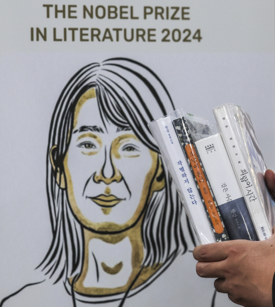 21일 서울 서초구 국립중앙도서관 본관 문학실에 마련된 한강 특별서가를 찾은 시민이 한강 작가의 책을 들고 있다. 뉴시스