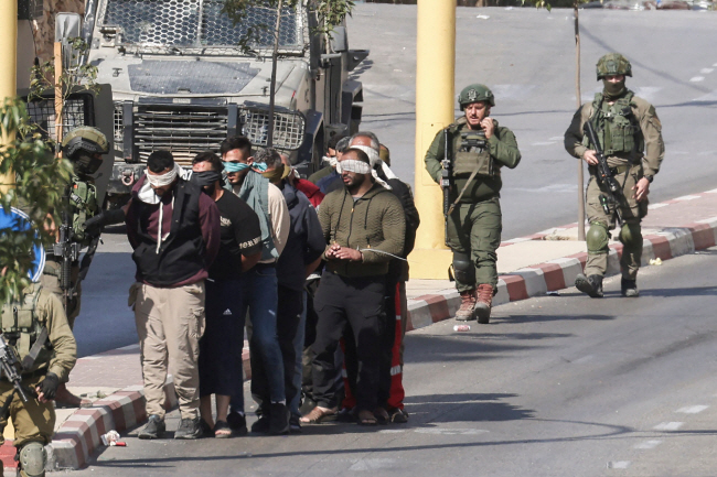 31일 요르단 강 서안지구 남부 도시인 헤브론에서 이스라엘 군인들이 붙잡은 팔레스타인인들의 눈을 가리고 손을 묶은 채 줄을 세워 끌고 가고 있다. AFP 연합뉴스