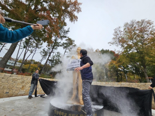 10일 오후 경북 경산시 영남대학교 박정희 동상에 이도건 씨가 밀가루를 뿌리고 있다. 연합뉴스