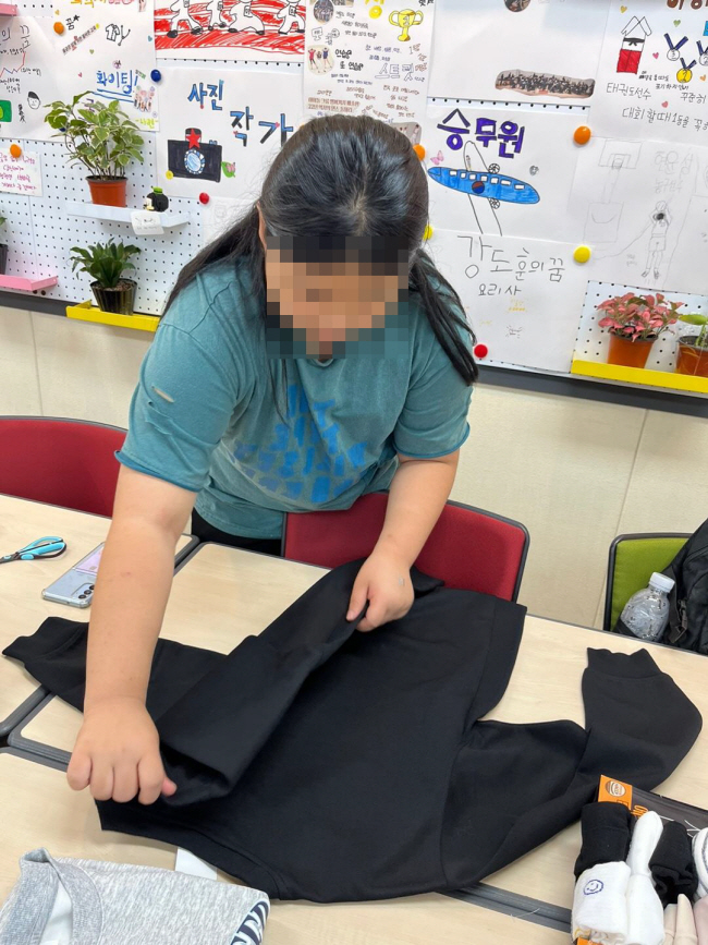 초록우산 가족돌봄아동 지원사업 대상 아동이 옷을 정리하는 방법을 배우고 있다.  초록우산 제공