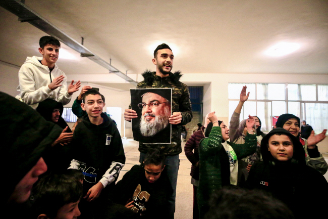 26일 레바논 남부도시 시돈의 한 학교에서 피란민들이 이스라엘과 헤즈볼라 간 휴전 소식에 지난 9월 이스라엘군 공습에 폭사한 전 헤즈볼라 수장 하산 나스랄라의 초상화를 들고 기뻐하고 있다.  EPA 연합뉴스