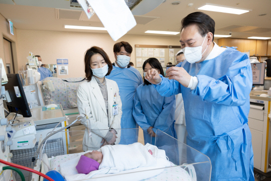 윤석열 대통령이 28일 서울성모병원에서 ‘이른둥이 지원 간담회’ 전 입원 중인 다섯쌍둥이의 다섯째를 살펴보고 있다. 연합뉴스.