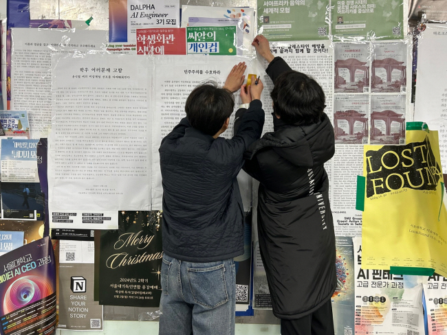4일 서울 관악구 서울대에서 학생들이 윤석열 대통령의 비상계엄 선포를 규탄하고 퇴진을 촉구하는 내용의 대자보를 게시판에 붙이고 있다. 이재희 기자