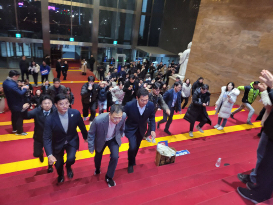 김상욱 국민의힘 의원(앞줄 가운데)이 7일 저녁 윤석열 대통령 탄핵소추안 표결을 위해 국회 본회의장으로 들어가고 있다. 더불어민주당 소속 신정훈 행정안전위원장(오른쪽)과 이해식 민주당 의원(왼쪽)이 동행했다.