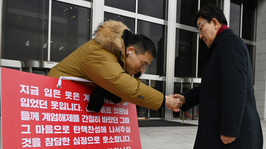 권성동 국민의힘 신임 원내대표가 13일 오전 서울 여의도 국회 본청 앞에서 윤석열 대통령의 탄핵을 촉구하며 1인시위 중인 김상욱 의원과 악수하고 있다.  박윤슬 기자