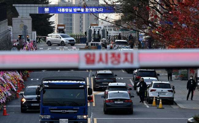 13일 서울 용산구 대통령실 입구 인근 도로에서 경찰들이 운전자의 신원을 확인하고 있다.    윤성호 기자