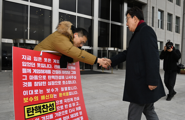 권성동(오른쪽) 신임 국민의힘 원내대표가 13일 오전 국회 본관 앞에서 윤석열 대통령 탄핵 촉구 1인 시위를 하고 있는 같은 당 김상욱 의원과 악수하고 있다.  박윤슬 기자