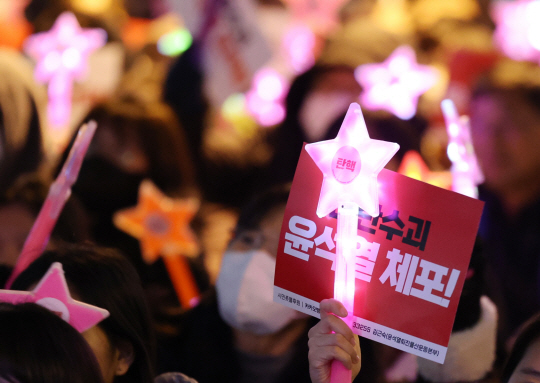 13일 오후 울산시 남구 롯데백화점 앞 광장에서 열린 ‘울산시민대회’에 참가한 시민이 피켓과 야광봉을 흔들며 윤석열 대통령의 탄핵을 촉구하는 구호를 외치고 있다. 연합뉴스