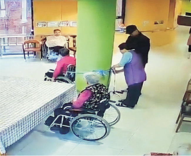 경기 지역 A 요양시설의 한 요양보호사가 노인이 탄 휠체어를 기둥에 묶고 있다.   독자 제공