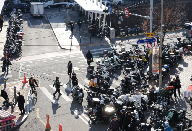 경기 침체에 비상계엄 및 탄핵 사태까지 겹치면서 연말연시 특수 분위기가 사라진 가운데 23일 서울의 한 전통시장 부근에 배달 오토바이들이  일감을 얻지 못해 대기하고 있다.  연합뉴스
