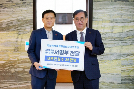 이승로(왼쪽) 성북구청장이 26일 국회에서 맹성규 국토교통위원장에게 강북횡단선 신속 재추진 서명부를 전달하고 있다. 성북구청 제공