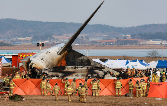 전남 무안국제공항에서 여객기 착륙 도중 충돌 사고가 난 29일 오후 무안국제공항에서 구급대원들이 기체 내부 탑승객 수색을 하기 위해 가림막을 설치한 뒤 수색 작업을 펼치고 있다. 뉴시스