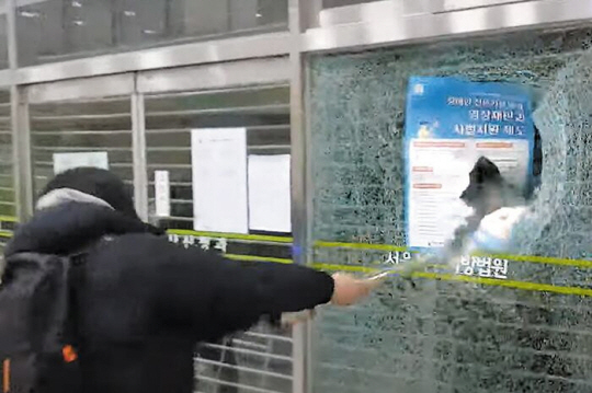 19일 새벽 윤석열 대통령에 대한 구속영장이 발부되자 윤 대통령을 지지하는 난동자가 서울서부지법 내 유리벽을 안내선 봉으로 깨트리고 있다. 유튜브 캡처