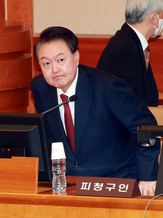 윤석열 대통령이 21일 오후 서울 종로구 재동 헌법재판소에서 열린 탄핵심판 3차 변론에 출석해 자리에 앉고 있다. 연합뉴스(사진공동취재단)