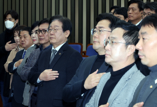 이재명(앞줄 오른쪽 네번째) 더불어민주당 대표와 박찬대(앞줄 오른쪽 세번째) 원내대표 등 의원들이 19일 서울 여의도 국회에서 열린 비상의원총회에서 국민의례를 하고 있다. 뉴시스