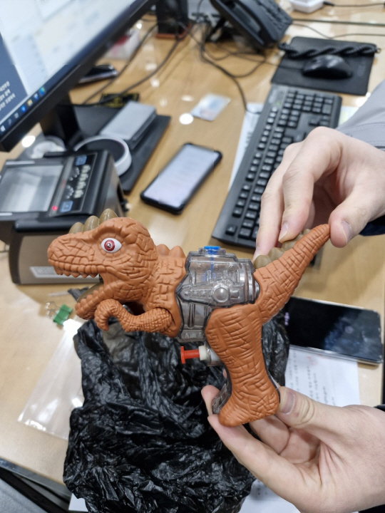 10일 오전 부산 기장군의 한 은행에서 강도 행각을 벌인 남성이 들고 있던 공룡 모양 물총. 범행 당시 검정 봉지에 쌓여 있었다. 부산 기장경찰서 제공