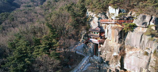 경산 와촌면 절집 불굴사의 산내 암자 홍주암. 수직의 바위가 벼랑을 이룬 자리에 들어섰다. 불굴사 법당에는 여성적인 느낌의 석불이 있는데, 갓바위 부처와 부부 사이라는 얘기가 전해진다.