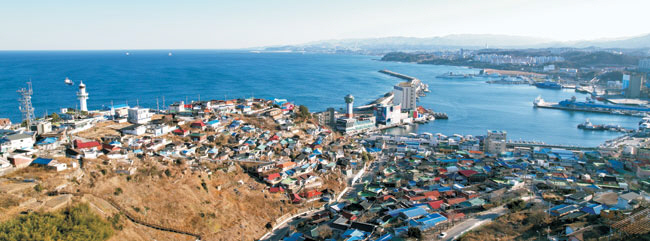 묵호항 일대가 내려다보이는 덕장마을의 가장 높은 자리에서 본 모습. 사진 왼쪽 등대 아래가 누추하고 좁은 달동네 골목에다 벽화를 그려 넣어 관광명소가 된 ‘논골담길’이다. 사진 오른쪽은 묵호의 과거 모습을 고스란히 간직하고 있는 주택가.