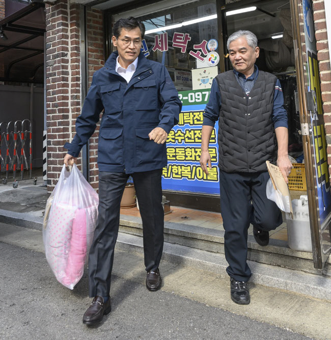 이기재(왼쪽) 서울 양천구청장이 ‘행복버블 찾아가는 세탁서비스’를 통해 깨끗하게 세탁된 겨울철 빨래를 다시 배달해주기 위해 세탁소를 나서고 있다. 양천구청 제공