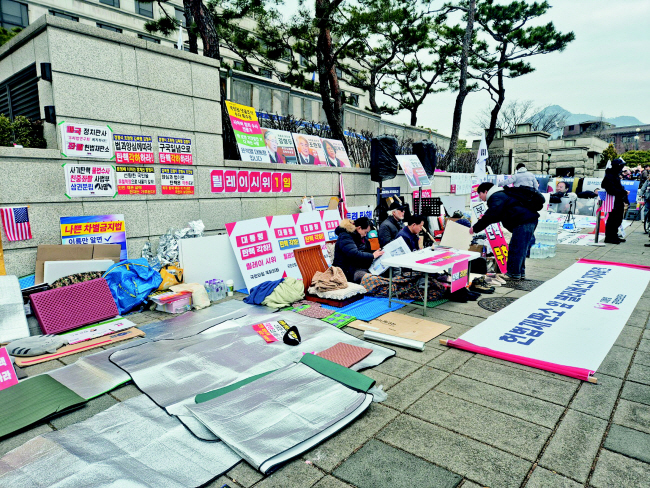12일 오전 서울 종로구 헌법재판소 앞 인도에서 탄핵 각하를 주장하는 시위대가 돗자리를 길게 이어 펼친 채 앉아 농성을 이어가고 있다. 노수빈 기자