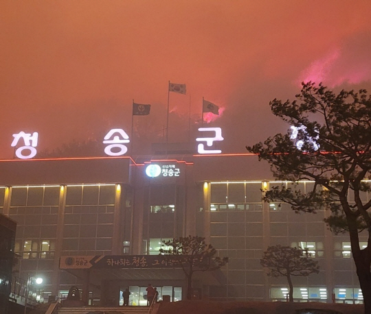 경북 안동지역 산불이 25일 오후 청송군으로 확산되면서 청송군청 뒷산이 불타면서 붉게 물들어 있다. 독자 제공