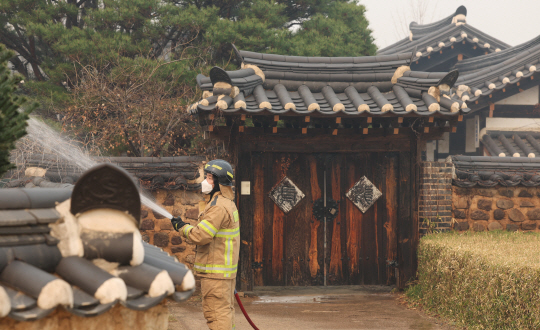 26일 경북 안동 하회마을에서 소방대원이 산불 불씨가 옮겨 붙지 않도록 마을 곳곳에 물을 뿌리고 있다. 연합뉴스