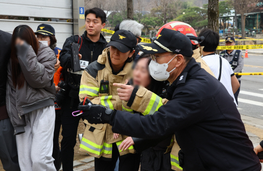 25일 오전 서울 강동구 명일초등학교 인근 도로에서 전날 발생한 싱크홀(땅 꺼짐) 사고 현장에 매몰돼 숨진 오토바이 운전자의 유가족이 소방대원의 부축을 받으며 이동하고 있다. 뉴시스