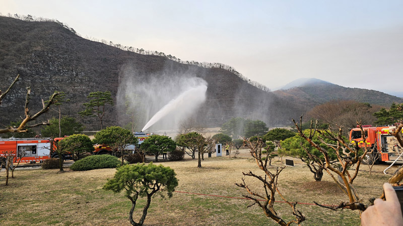 26일 오전 경북 안동시 풍천면 병산서원 건너편 산 너머로 산불로 보이는 연기가 몰려오자 소방대원들이 불길이 덮칠 것에 대비해 주변에 물을 뿌리고 있다. 연합뉴스