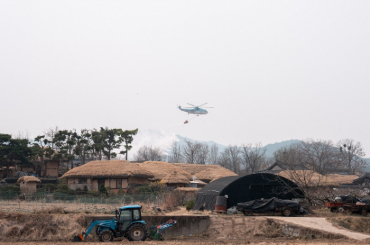 의성 산불이 엿새째 이어지고 있는 27일 경북 안동시 풍천면 하회마을에서 헬기가 문화재, 주요 시설 등의 방어을 위해 예비 주수하고 있다. 뉴시스