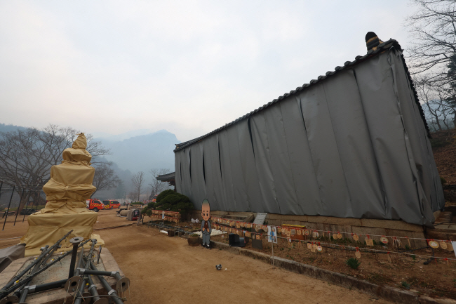 27일 경북 청송군 주왕산면 대전사 삼층석탑과 보광전이 산불 피해를 막기 위해 설치된 대형 방염포로 감싸여 있다. 연합뉴스