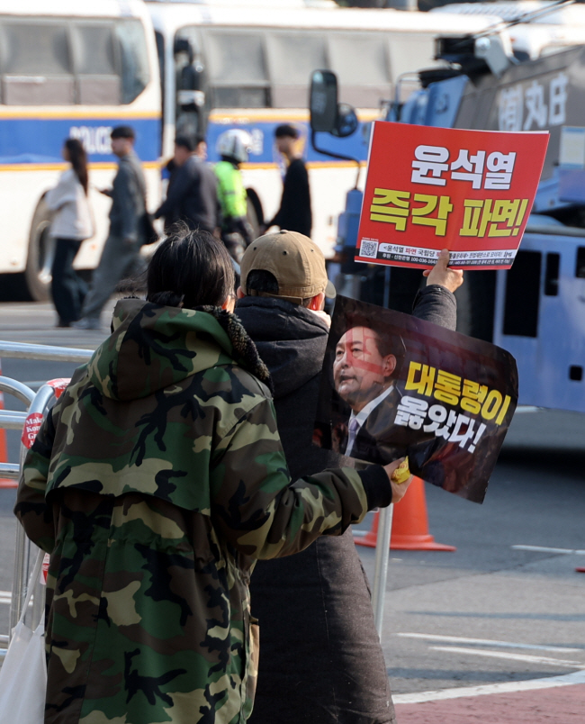 윤석열 대통령 탄핵심판 선고기일을 이틀 앞둔 2일 오전 서울 종로구 안국역 인근에서 탄핵 반대 지지자와 탄핵 지지자가 각각 팻말을 들고 있다.   박윤슬 기자